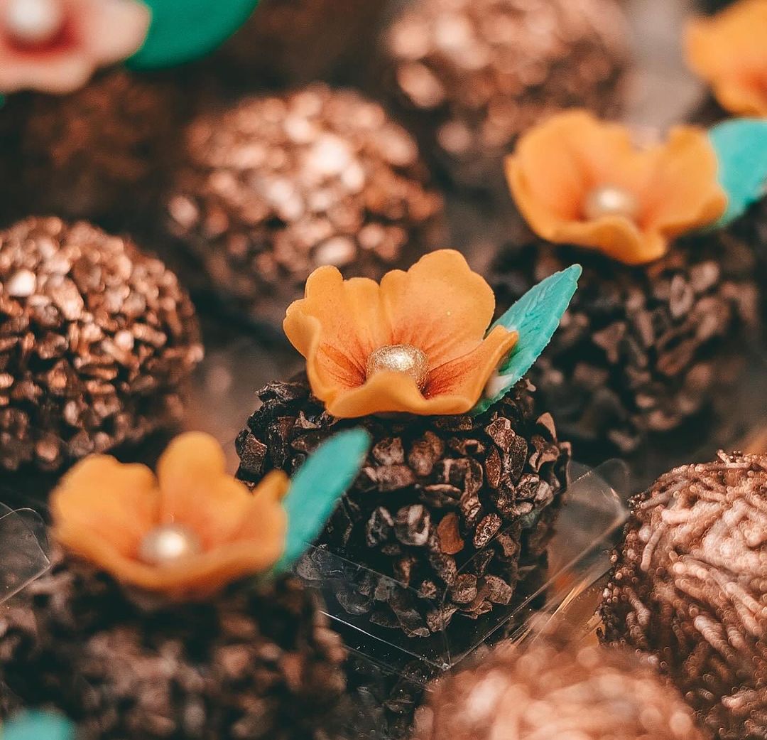 Brigadeiros de chocolate com mini flores de açúcar em tom laranja