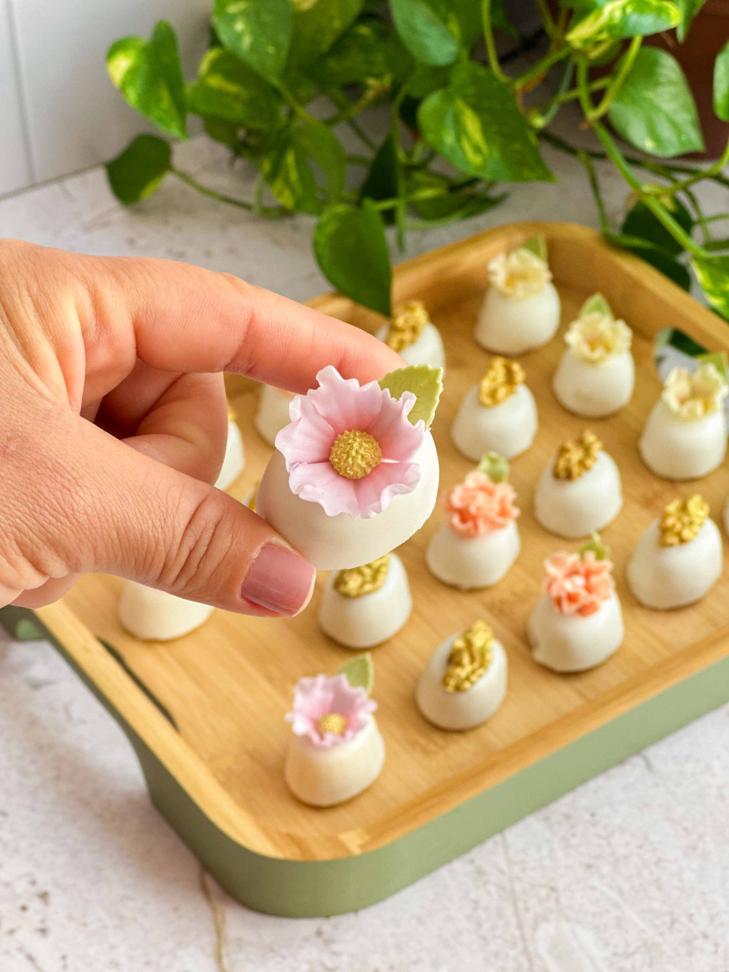 Mão segurando brigadeiro branco com mini flor rosa