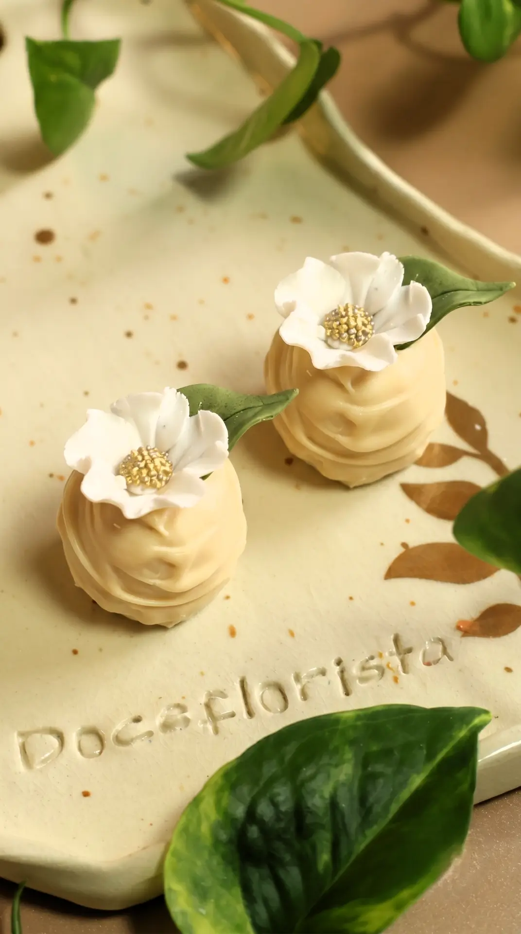 Dois brigadeiros com mini flores brancas em prato artesanal