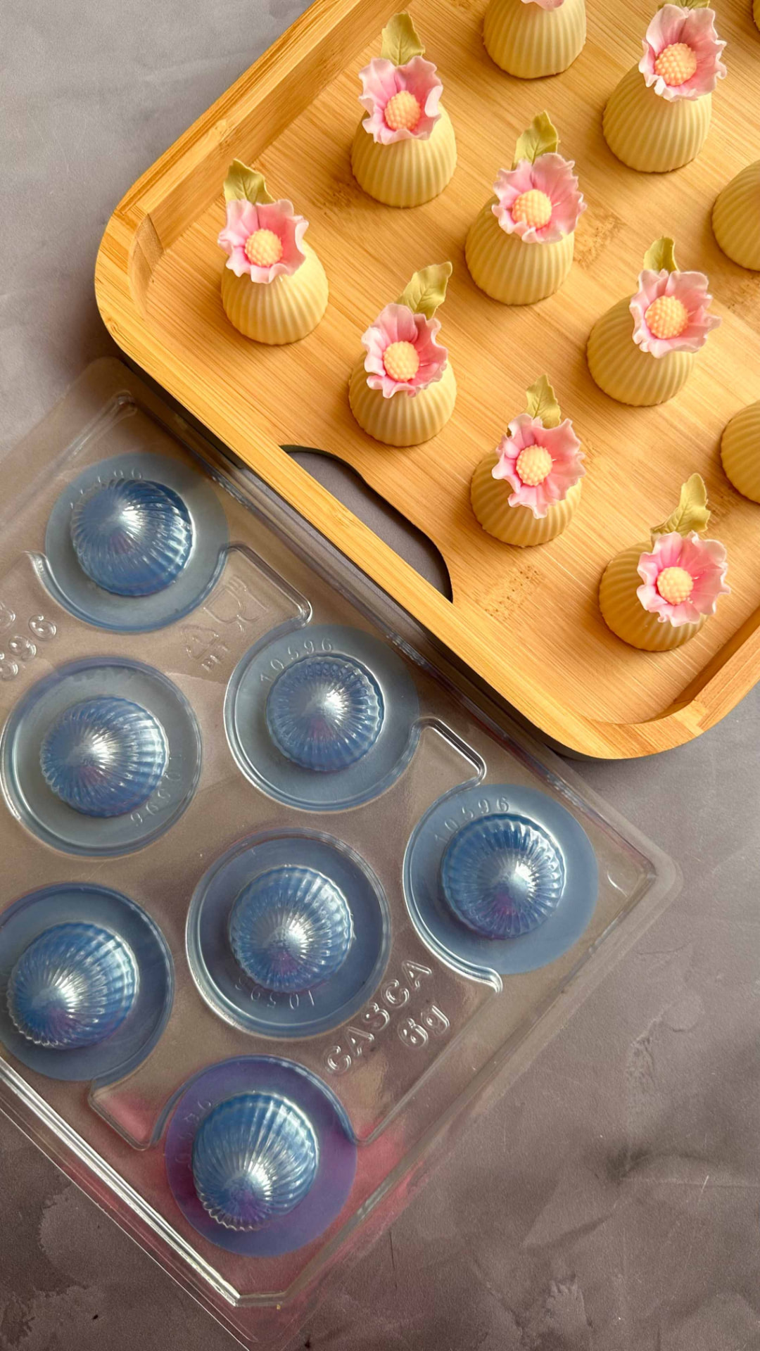 Bandeja de brigadeiros com mini flores rosa ao lado de forma de acetato